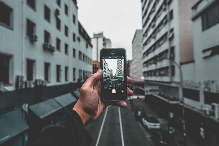 man holding smartphone capturing roadway